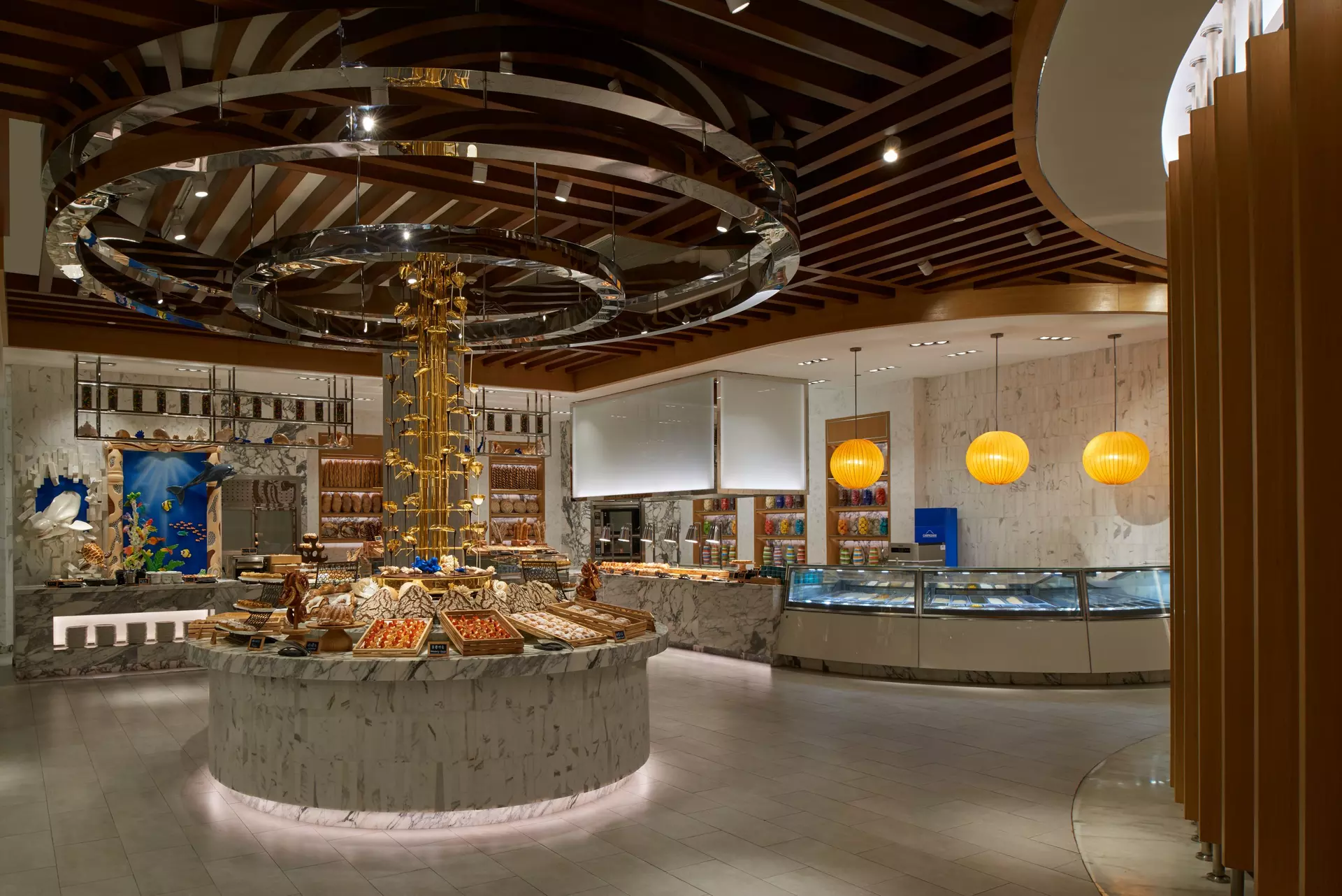 The bakery and gelato counter at Saffron, breads and pastries on marble beneath a mirrored ring chandelier